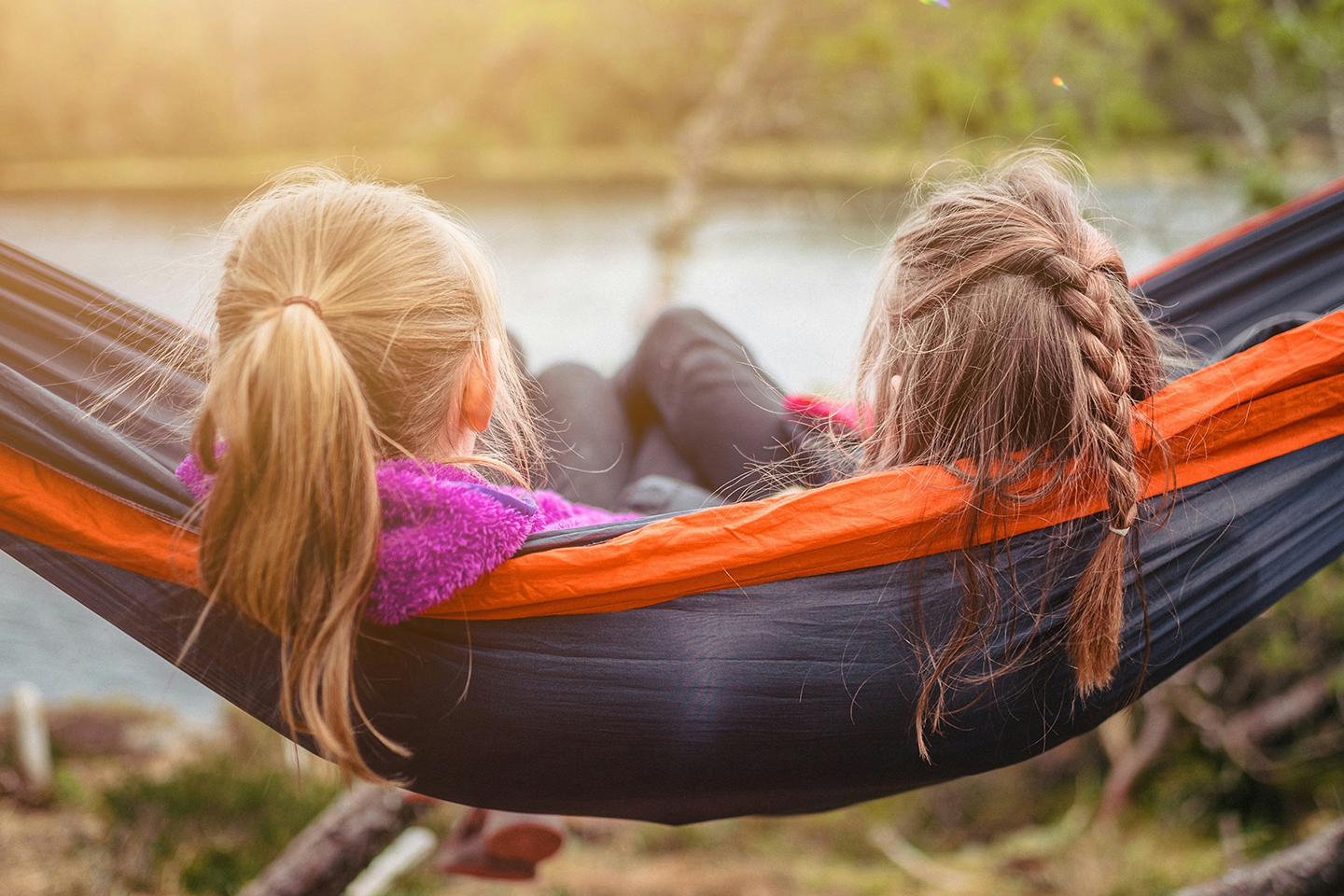 Two young girls sat on a hammock by a lakeside with their backs to the cameras. Seen but not heard: the child’s voice in the family court system