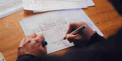 A man's hands drawings architectural floorplan drawings. Who owns the copyright after you pay an architect for drawings or plans? —The Times