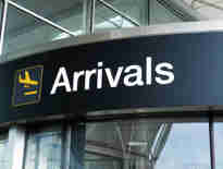 Russell-Cooke immigration law charging information. Image of airport arrivals signage above a glass door.