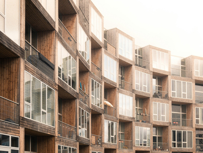 The picture shows a curved, cladded building with balconies. 