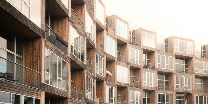 The picture shows a curved, cladded building with balconies. 