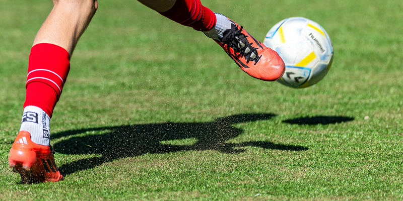 Image of football being kicked on pitch. 