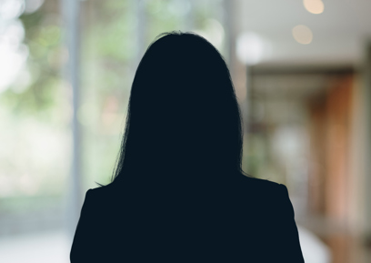 Russell-Cooke Solicitors staff photograph. Silhouette of a female team member against the backdrop of an office window and corridor with a soft focus effect.
