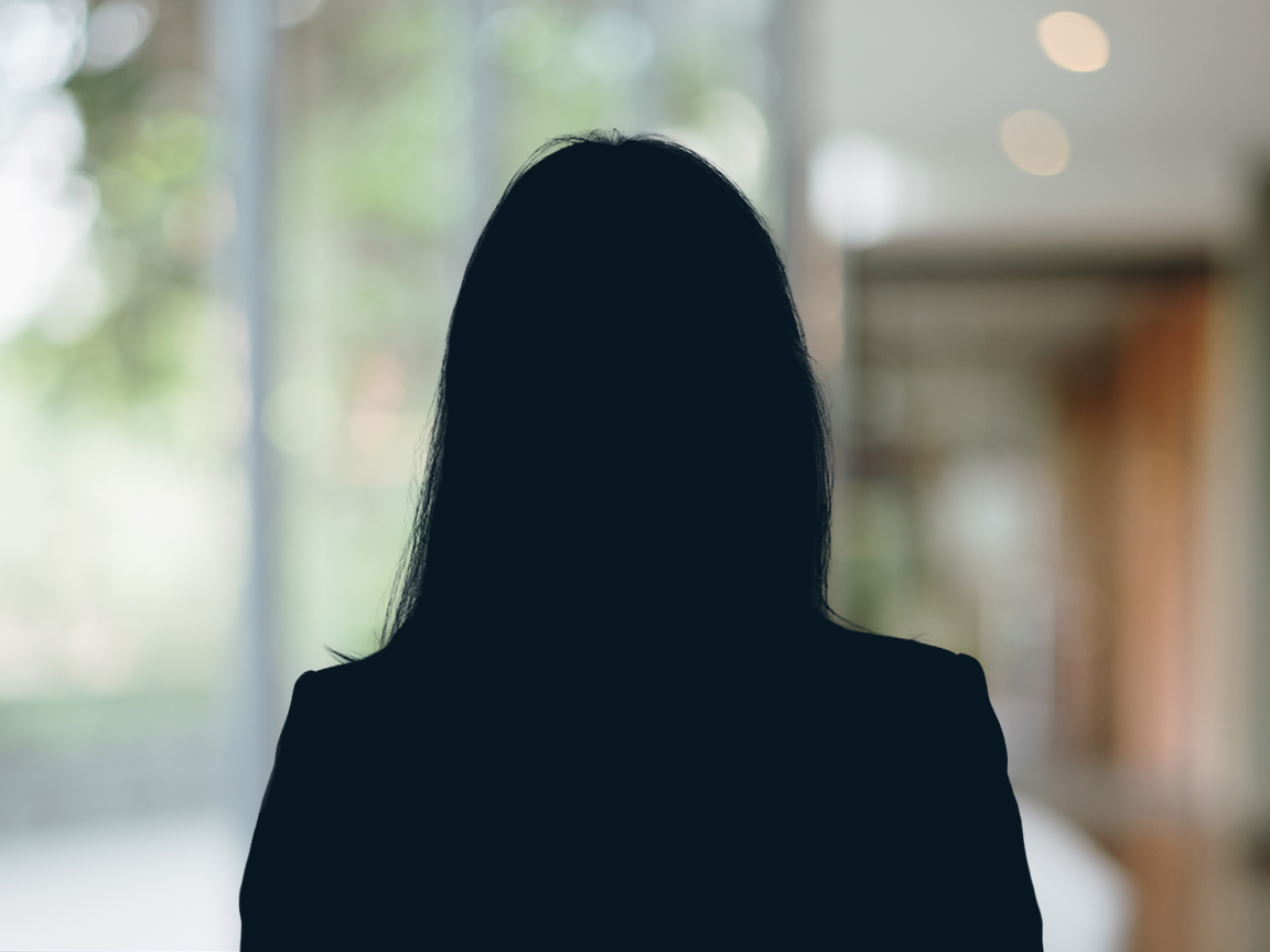 Russell-Cooke Solicitors staff photograph. Silhouette of a female team member against the backdrop of an office window and corridor with a soft focus effect.