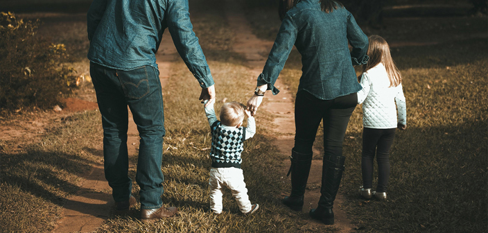 A family of four holding hands walking through a woods. Criminal Injuries Compensation Authority (CICA) claims solicitors