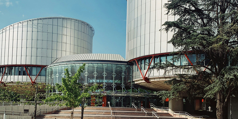 The image shows the facade of the European Court of Human Rights in Strasbourg, France.