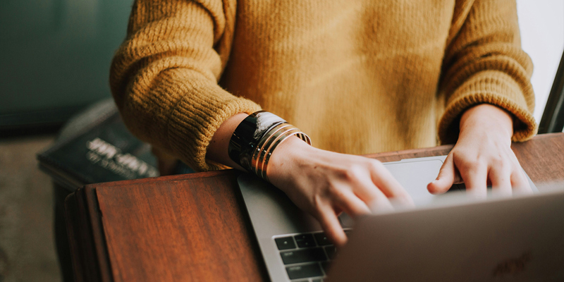 A woman in a mustard jumper and bangles typing on her laptop. Updating the law is welcome but digitising wills comes with risks—The Times