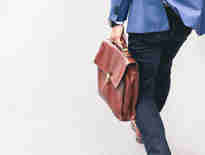 Russell-Cooke employment litigation charging information. Man walking and carrying a brown leather work bag. 