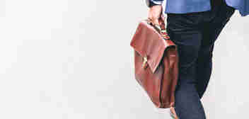 Russell-Cooke employment litigation charging information. Man walking and carrying a brown leather work bag. 