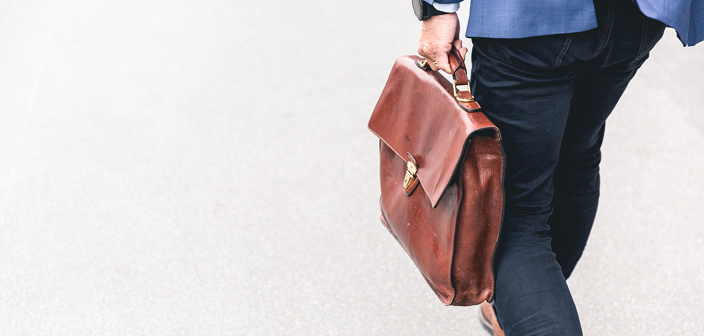 Russell-Cooke employment litigation charging information. Man walking and carrying a brown leather work bag.