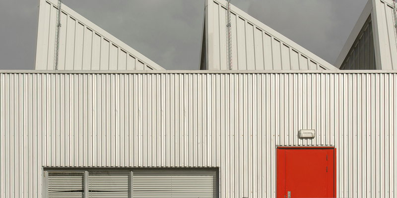 An industrial site with metal walls and roofs and a spiral staircase and a red door. Russell-Cooke advises Bloom-Crosstree joint venture on £20.75m acquisition of two industrial sites in Ealing and Enfield