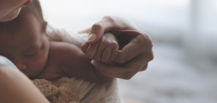 A new born baby holding onto their mothers finger. Russell-Cooke, birth injury solicitors