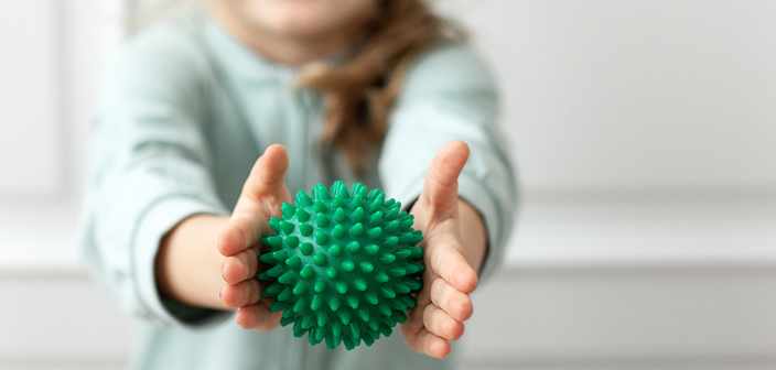 A young toddler holding green rubber physio ball in the foreground. Multi Trauma injury claims solicitors