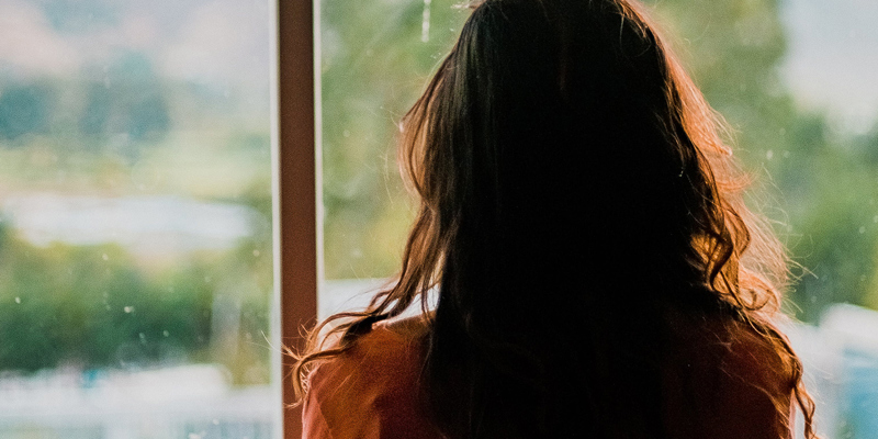 A lady looking out onto greenery through a window.  Lost people—has anyone seen my beneficiary?