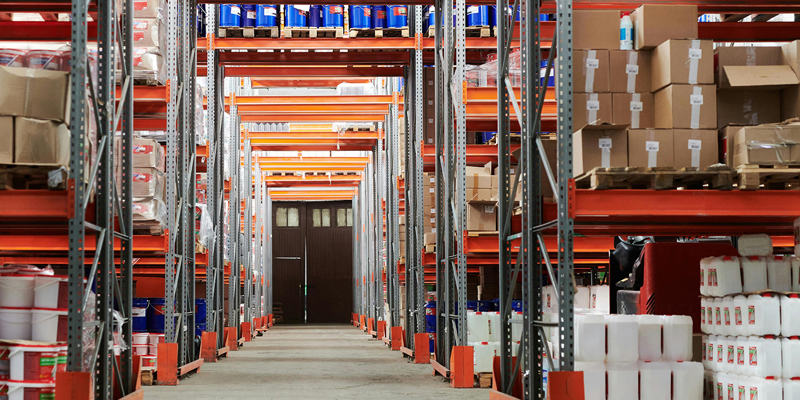 The image shows a storage facility with aisles of boxes. Russell-Cooke advises Shurgard UK Limited on £30m acquisition of two storage facilities