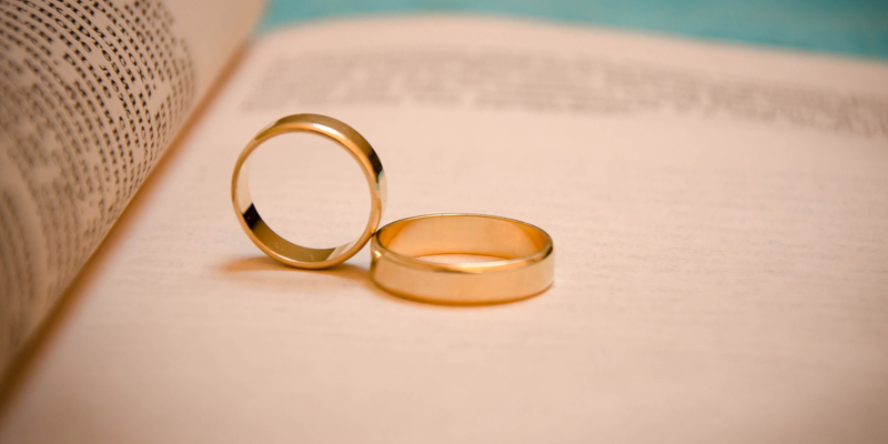 Two wedding rings on a book. UK Marriages Decline Russell Cooke