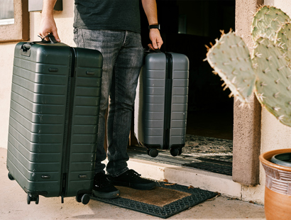 Man carrying suitcases in front of the main house door