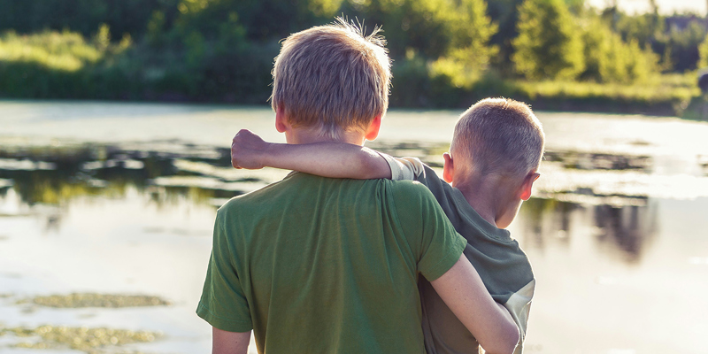Two brothers in arms in front of a lake. Brain Injury Claims Solicitors