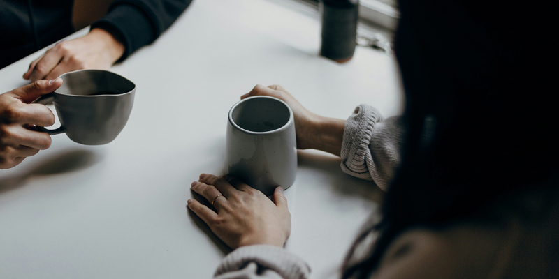 Two people across from a table with a cup of tea and coffee each. The image is darkened suggesting a sombre mood. A guide for family lawyers supporting separating couples— Thought Leaders 4