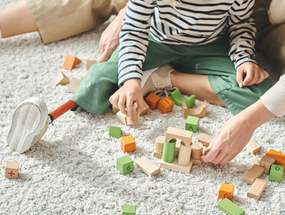 A young boy, with a prosthetic leg, playing with bricks on a carpet. Amputation Injury Claims Solicitors