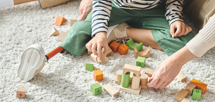 A young boy, with a prosthetic leg, playing with bricks on a carpet. Amputation Injury Claims Solicitors