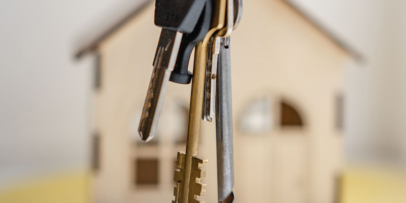 A model house in the background with a set of keys held in the foreground. How to pass on our properties equally to our children: gift or sell cheaply?—Financial Times