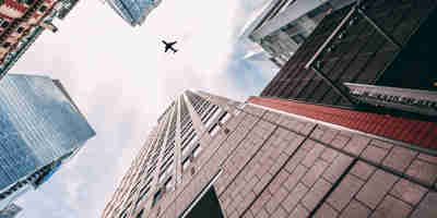 Russell Cooke Corporate Redomiciliation: Passenger jet flying high over corporate rea estate buildings