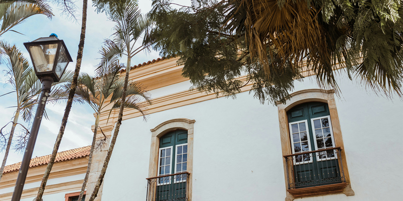 Exterior facing wall of Spanish house showing windows and branches of trees