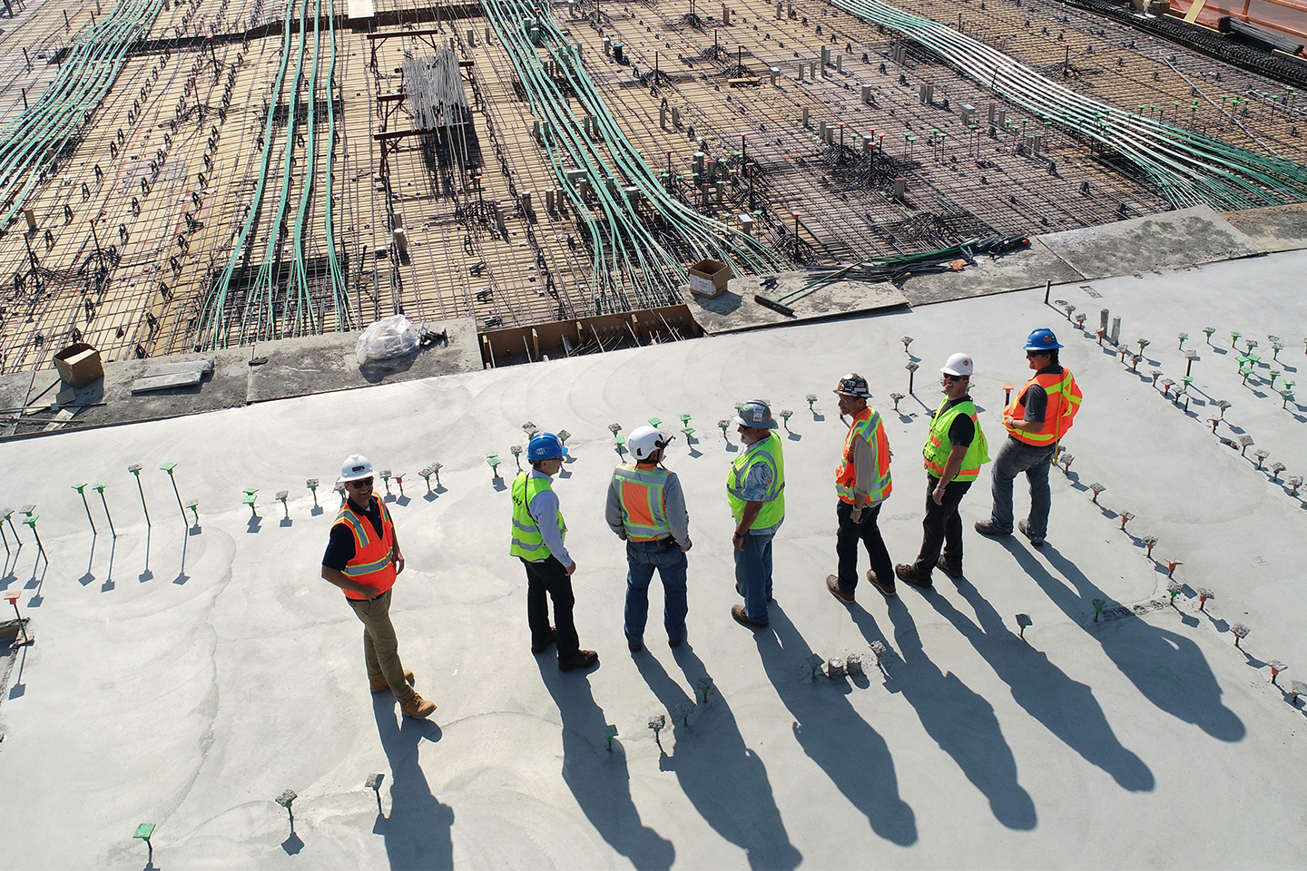 Construction men in high-vis vests and safety hats, lined up on a construction. Previewing the upcoming Joints Contracts Tribunal (JCT) 2024 suite of contracts site. 