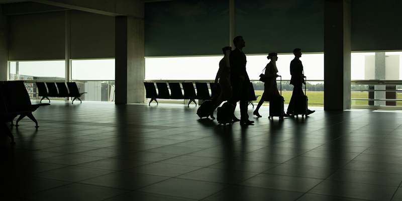 Individuals walking with suitcases at an airport