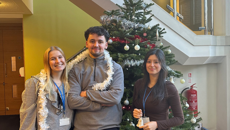 Russell-Cooke trainees by a Christmas tree. 