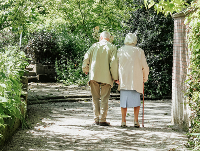 Elderly couple walking hand-in-hand in a leafy footpath. Lessons on immigration compliance for businesses–sponsor licence revoked for care home group