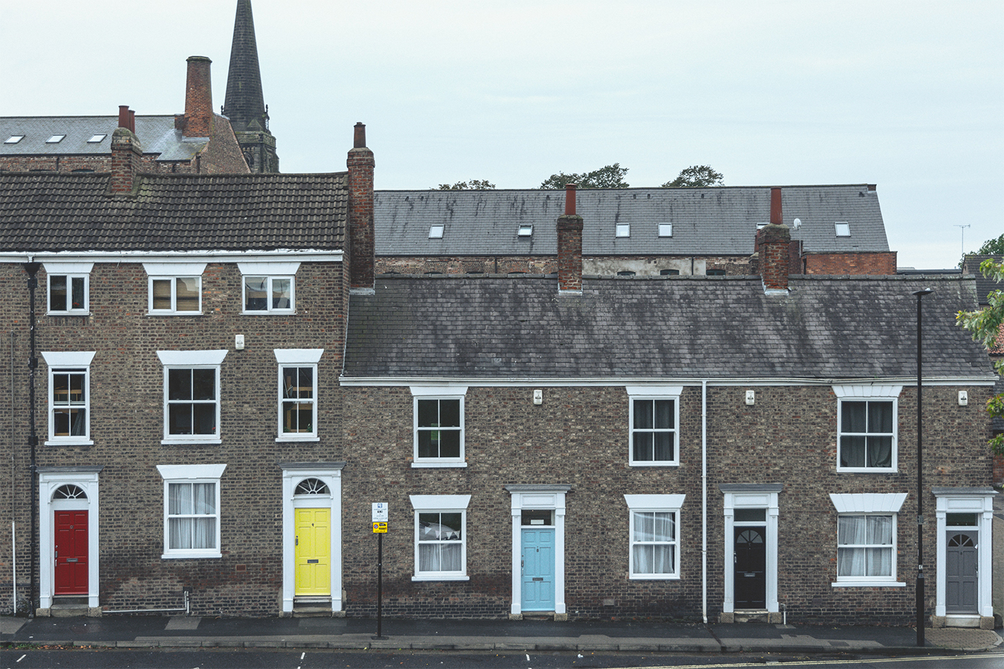 Georgian townhouses in the UK with colourful painted doors and a church spire in the background.Renters Reform Bill update —the future landscape of private renting  