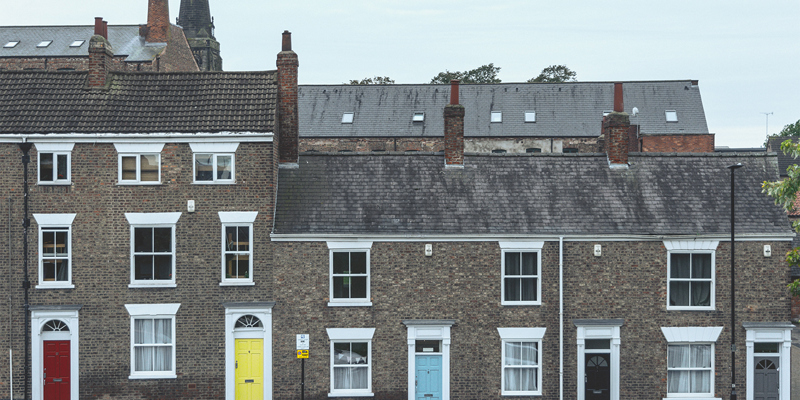 Georgian townhouses in the UK with colourful painted doors and a church spire in the background.Renters Reform Bill update —the future landscape of private renting
