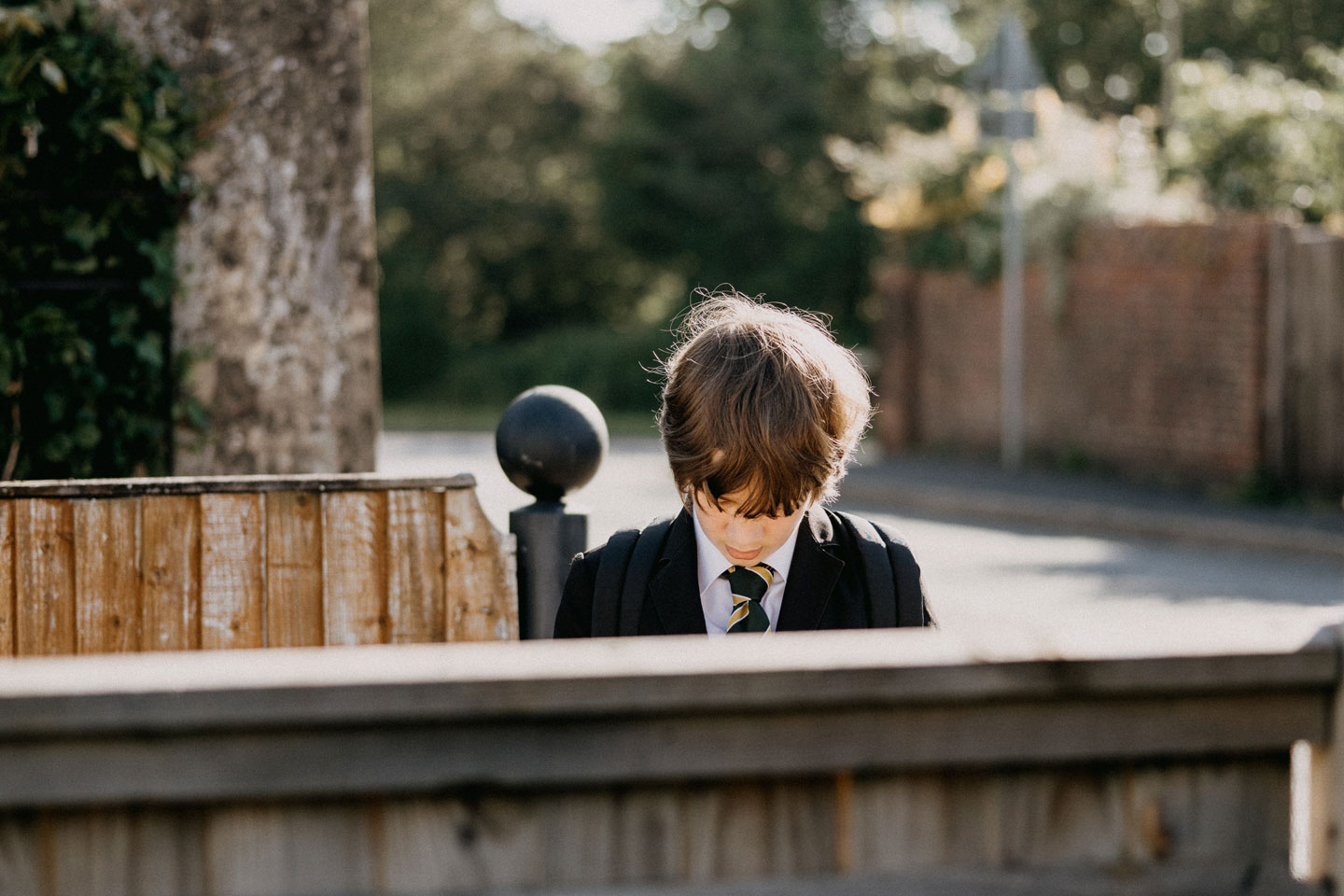 Russell-Cooke education law. An image of a school boy in uniform, stood behind a fence and looking down at the ground.