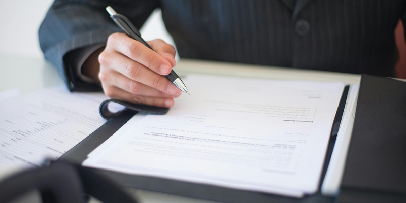 This picture shows an employment contract and someone signing it. 