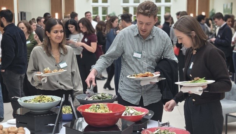 The image shows three people serving food at a buffet. All three are trainee solicitors at Russell-Cooke.