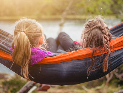 Two young girls sat on a hammock by a lakeside with their backs to the cameras. Seen but not heard: the child’s voice in the family court system