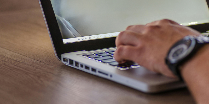 A male hand typing on a laptop. Russell-Cooke advises the shareholders of Simpson Associates on their investment from Beech Tree Private Equity