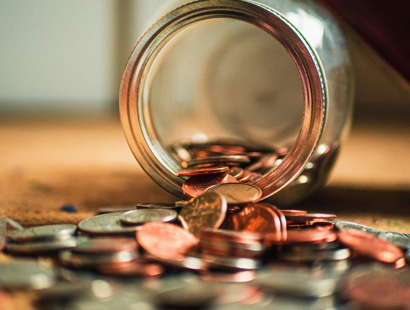 A glass jar pouring coins onto the table. The Autumn Statement and your money—Financial Times