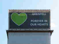 Image of a banner covering the Grenfell Tower. The banner has a large green heart and the words 