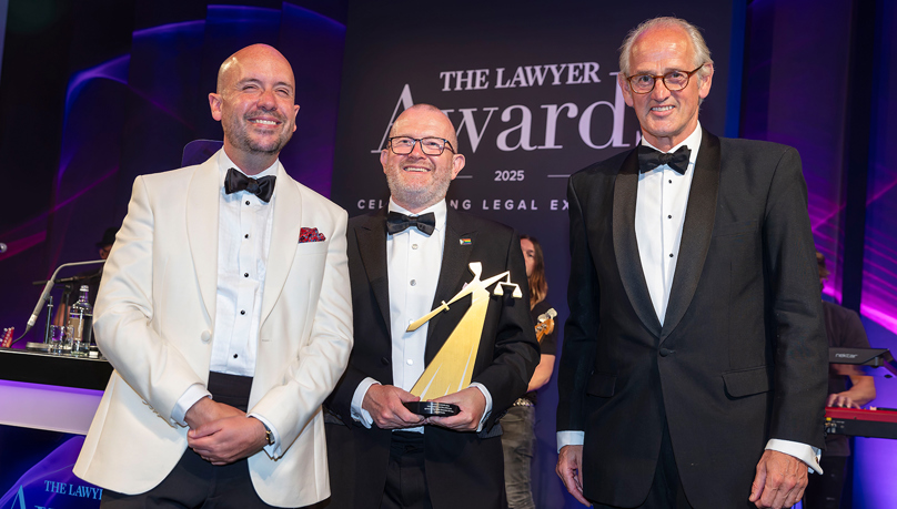 Three men smiling in black tie - the left man is in white blazer and the two men on the right are in black blazers. The man in the middle is holding the trophy. Russell-Cooke scoops Law Firm of the Year: The Independents at The Lawyer Awards