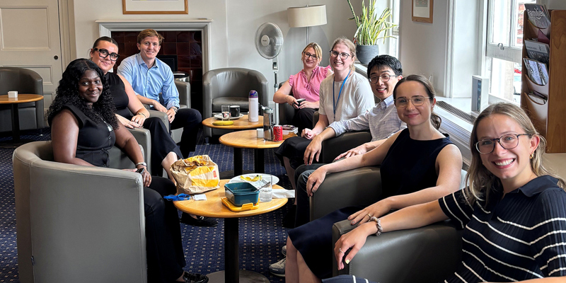 The picture shows a group of people sitting in armed chairs.