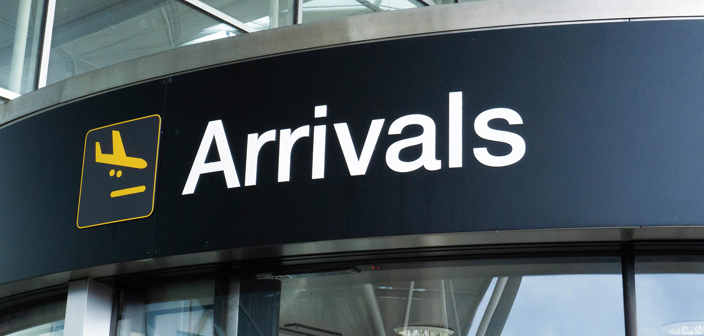 Russell-Cooke immigration law charging information. Image of airport arrivals signage above a glass door.