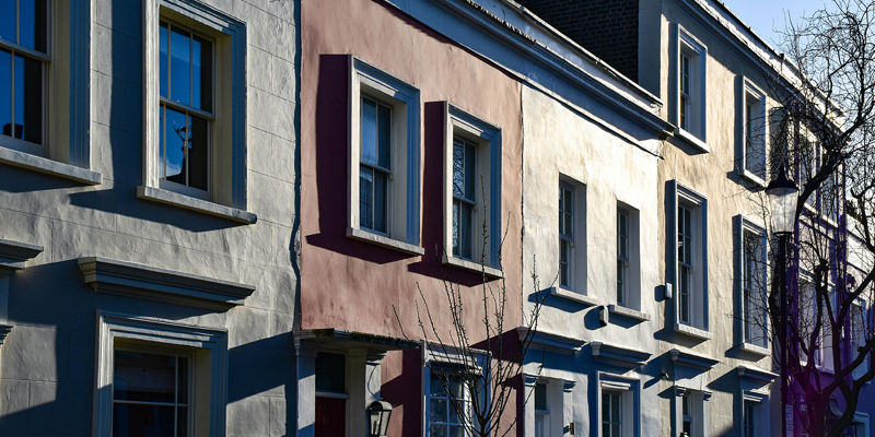 Colourful Victorian terraced houses in London with the afternoon light beaming on the facades of the property. 