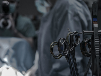Surgical instruments in the foreground and surgeons operating in the background. Medical Practitioners Tribunal’s investigation into mesh surgeon, Mr Anthony Dixon