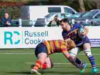 Action shot of wo opposing players from a Cobham RFC match Russell-Cooke sponsored banner in the background