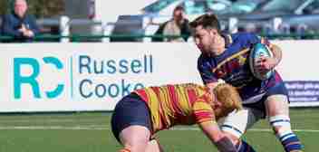 Action shot of wo opposing players from a Cobham RFC match Russell-Cooke sponsored banner in the background